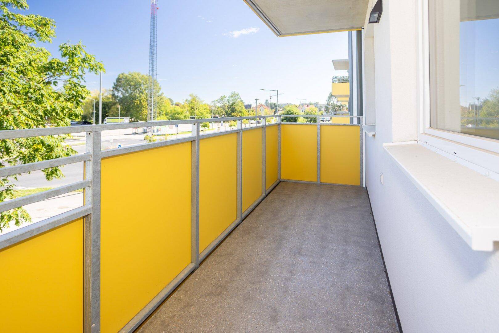 Moderner Balkon mit gelben Sichtschutzelementen und Metallgeländer.