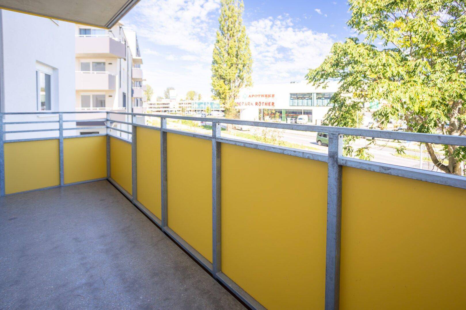 Heller Balkon mit gelben Paneelen und Blick auf die Umgebung.