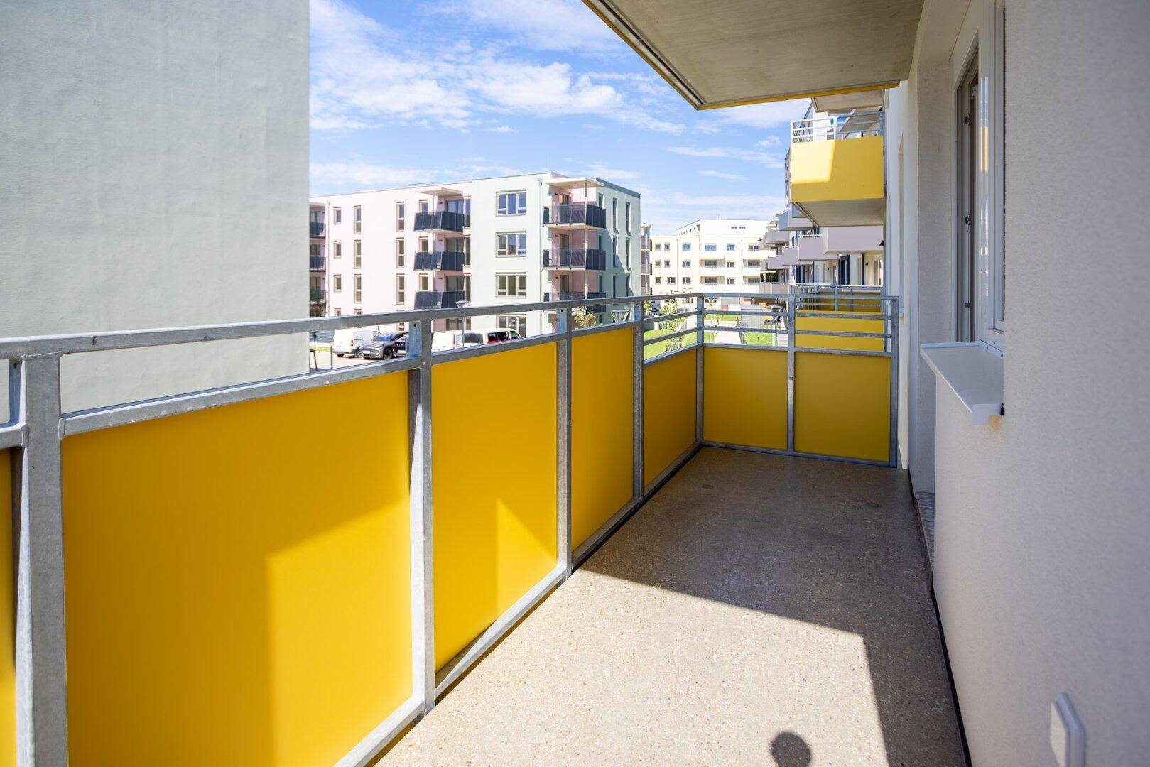 Heller Balkon mit gelben Sichtschutzelementen und Blick auf die umliegenden Gebäude.