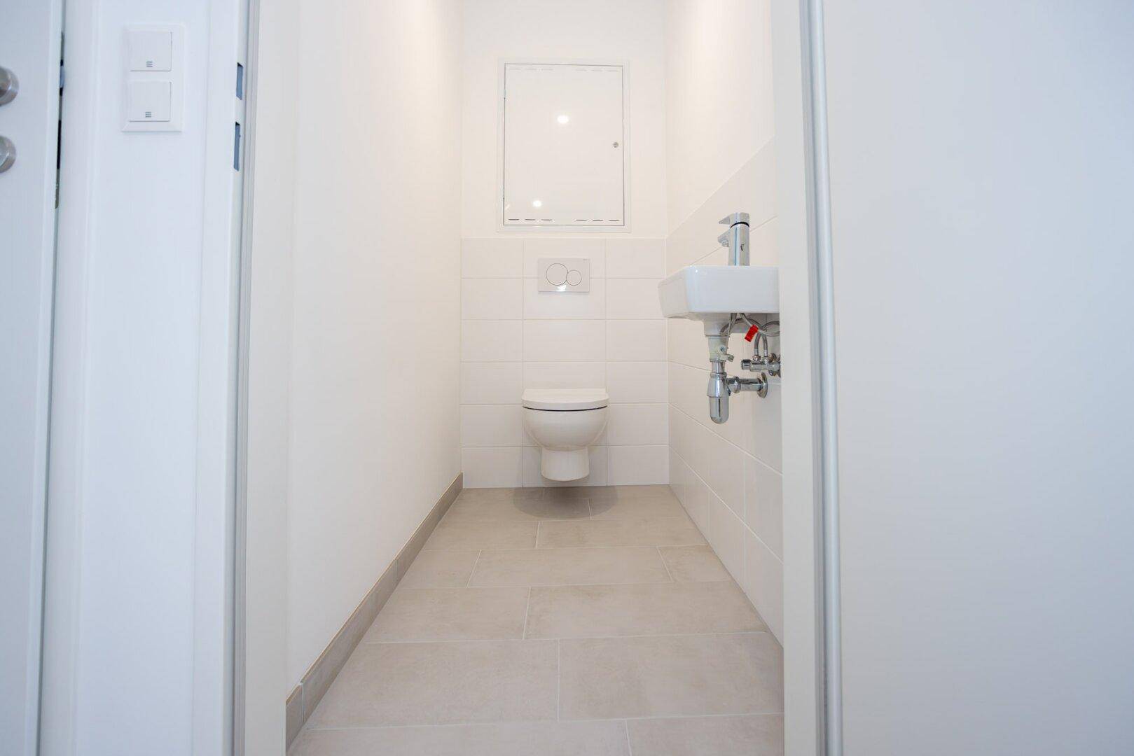 Kleines Gäste-WC mit wandhängender Toilette und Handwaschbecken.
