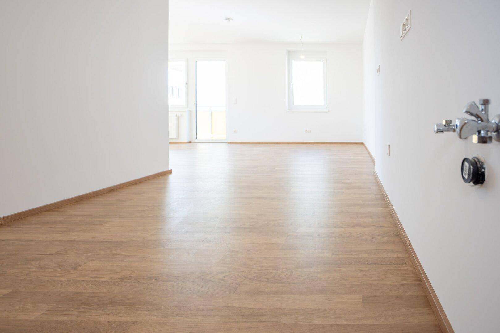 Heller Flur mit Laminatboden und Anschlüssen für eine mögliche Küchenzeile.