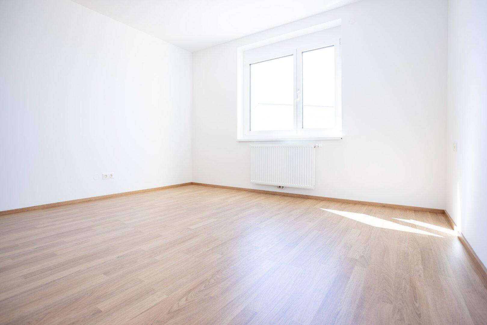 Unmöbliertes Schlafzimmer mit hellem Laminatboden und weiß gestrichenen Wänden.