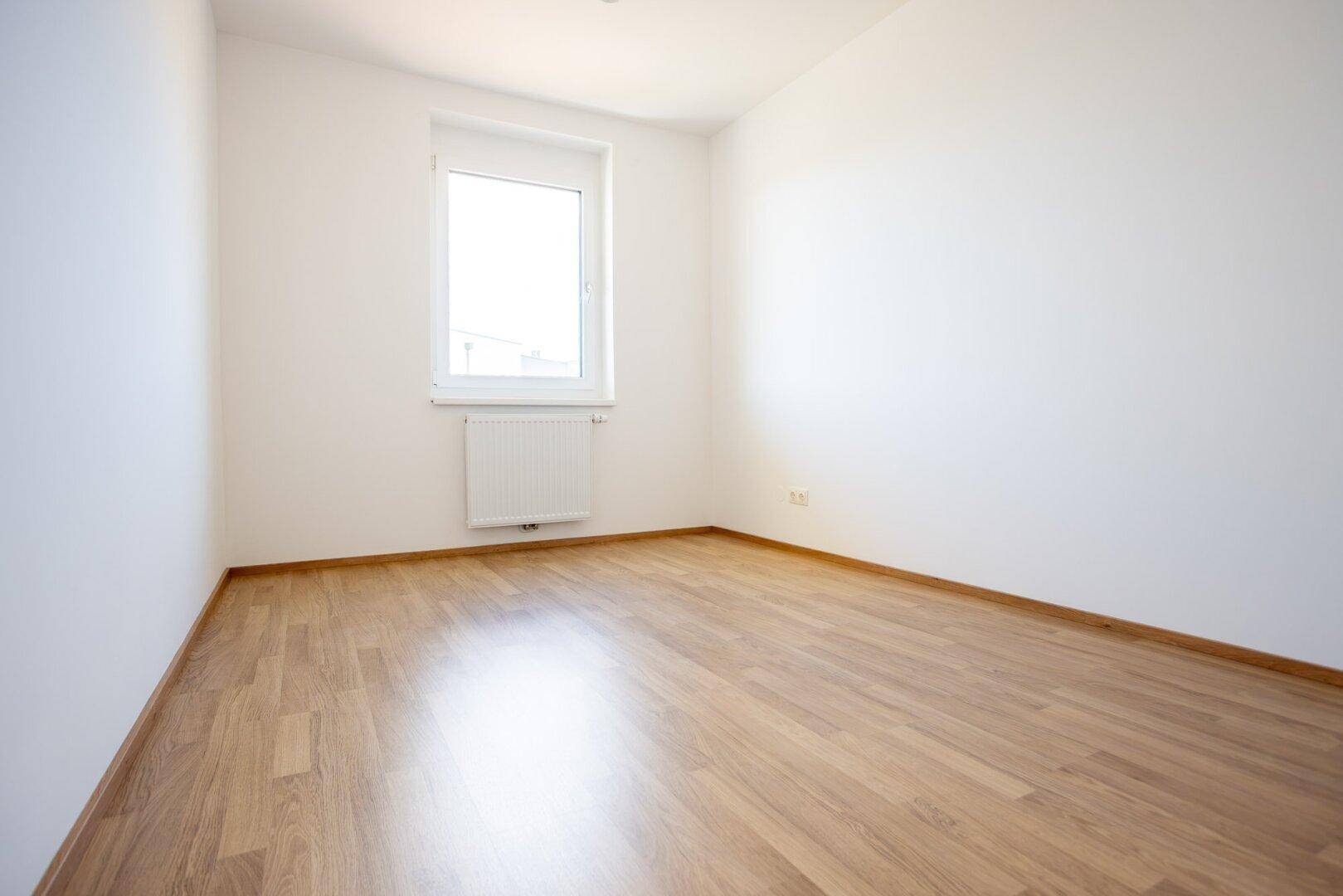 Heller Raum mit Laminatboden und weiß gestrichenen Wänden, bietet viel Gestaltungspotenzial.