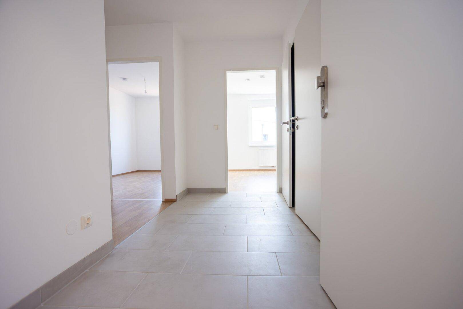 Heller Flur mit Fliesenboden, der zu verschiedenen Räumen der Wohnung führt.