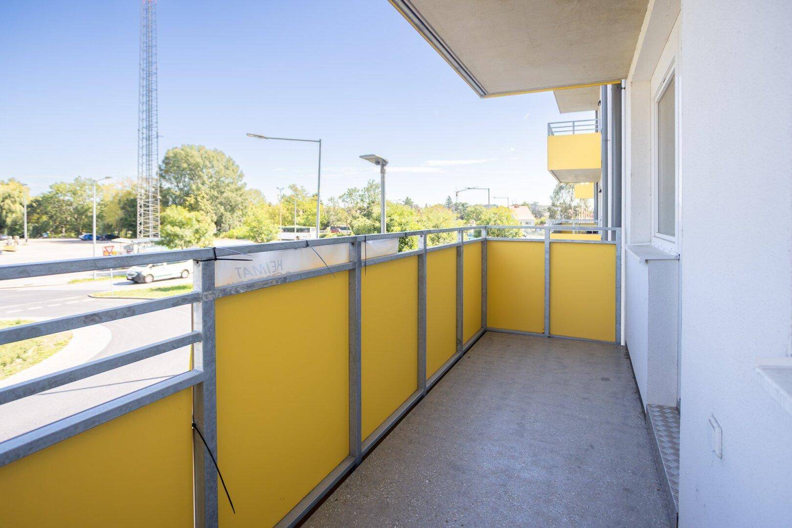 Heller Balkon mit gelben Sichtschutzelementen und Blick auf die Umgebung.