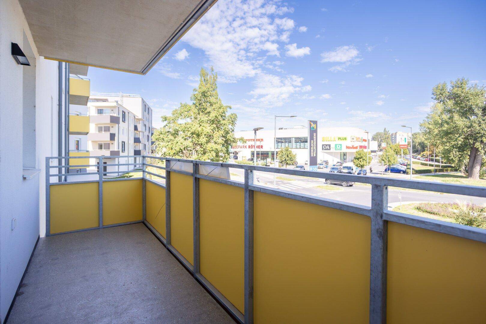 Geräumiger Balkon mit gelben Paneelen und Ausblick auf die städtische Umgebung.
