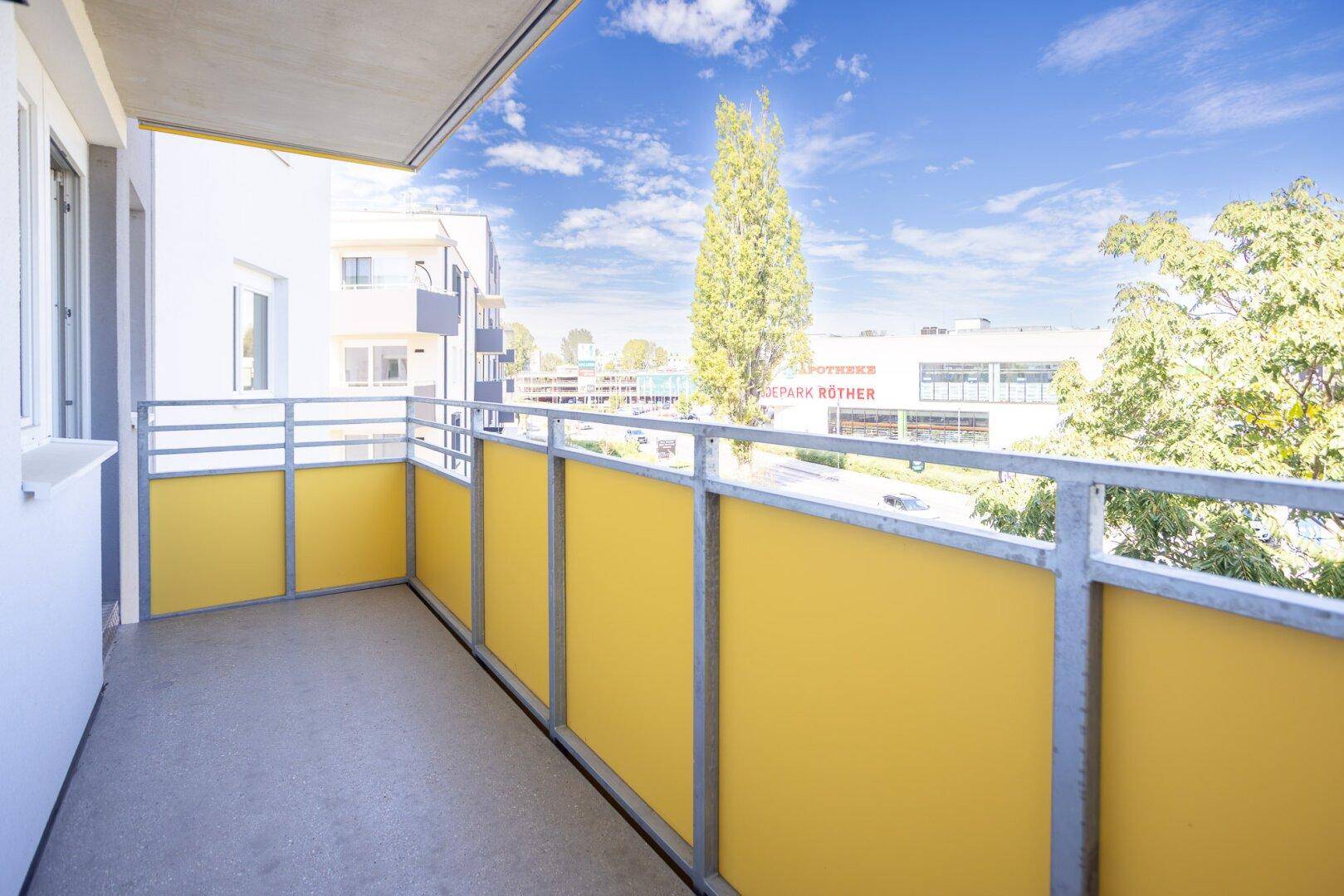 Geräumiger Balkon mit gelben Sichtschutzelementen und Blick auf die Umgebung.