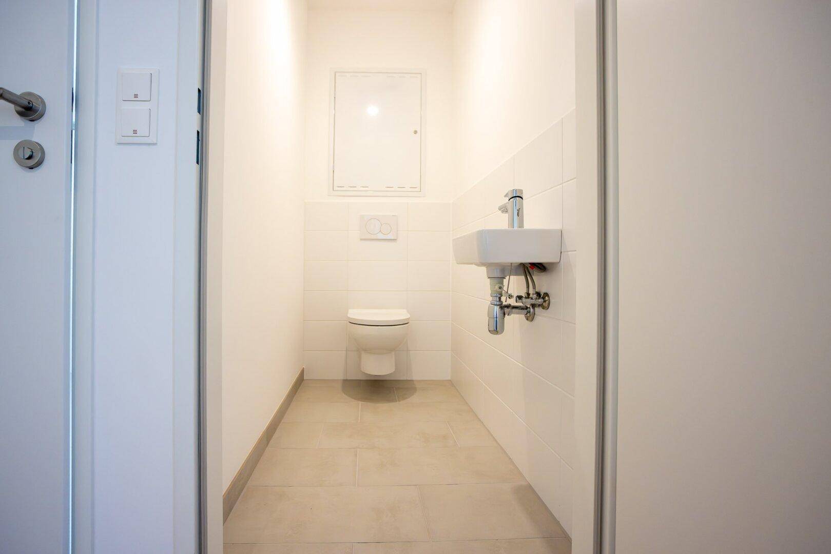 Kleines Gäste-WC mit wandhängender Toilette und Handwaschbecken.