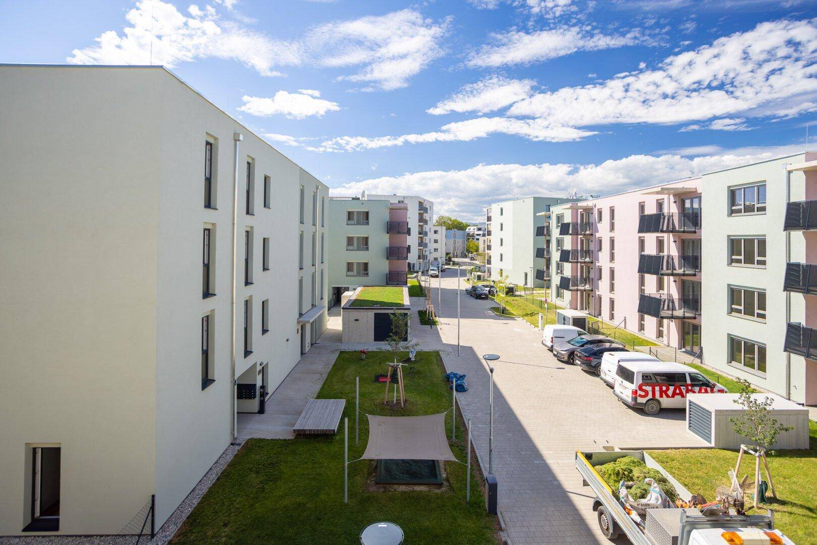 Weitläufige Ansicht der modernen Wohnsiedlung mit Gebäuden, Straßen und gepflegten Grünflächen.