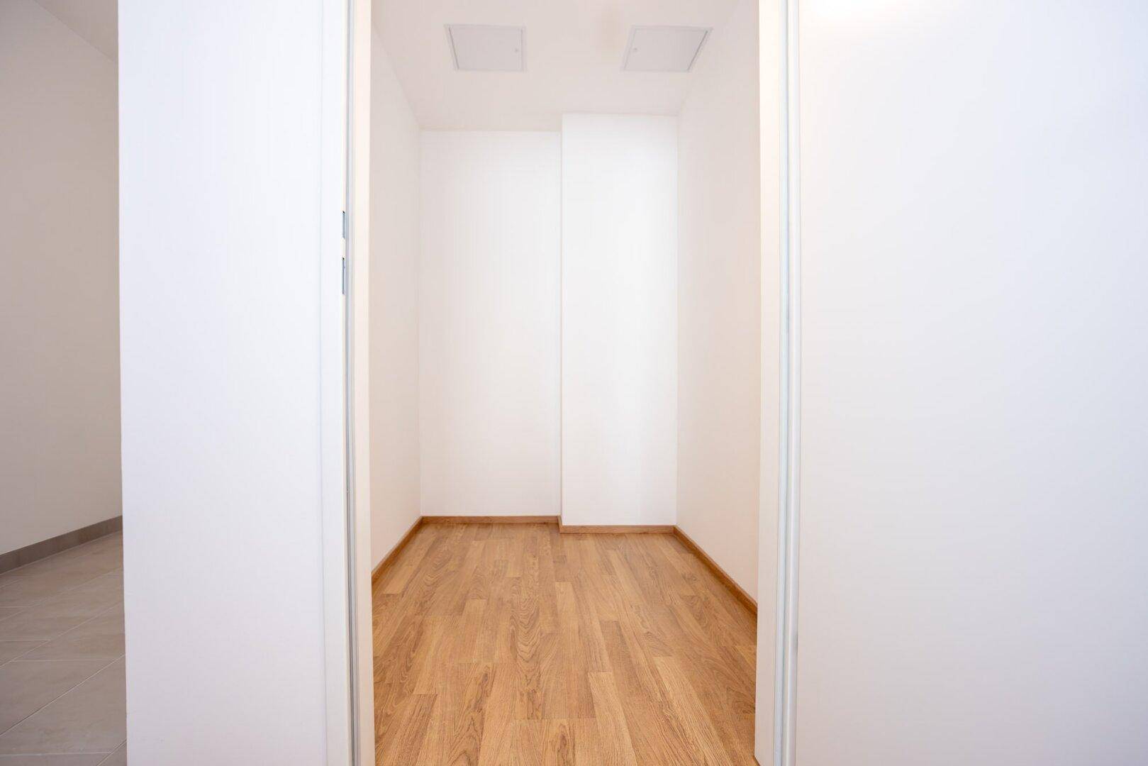 Kleiner Abstellraum mit hellem Laminatboden und weißen Wänden, ideal für zusätzlichen Stauraum.