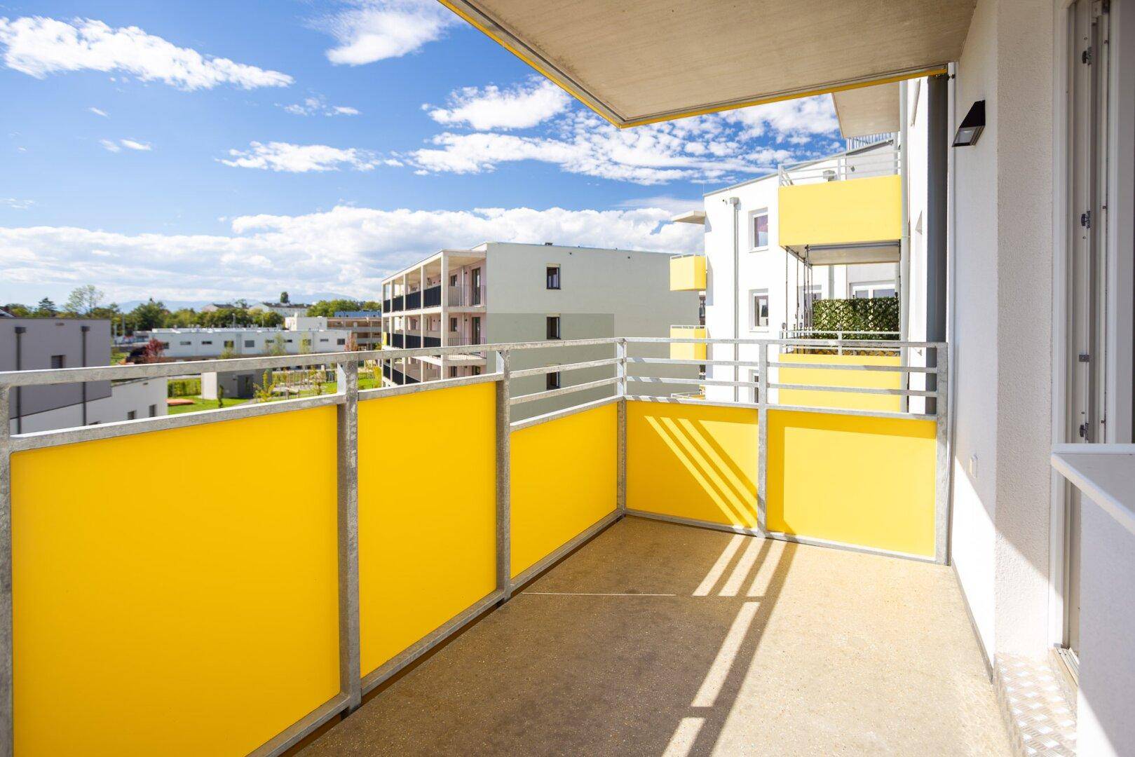 Heller Balkon mit gelben Sichtschutzpaneelen und Blick auf die umliegenden modernen Gebäude.