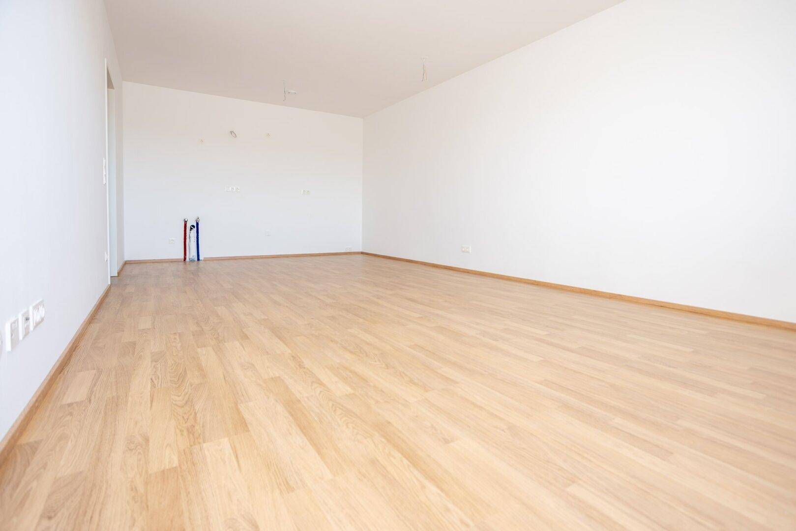 Unmöblierte Küche mit Laminatboden und weißen Wänden, bereit für die Installation einer modernen Einbauküche.