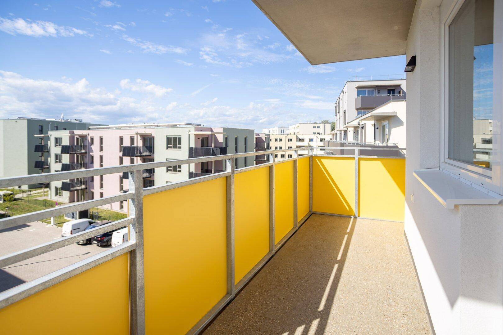 Moderner Balkon mit gelben Sichtschutzpaneelen und Blick auf die umliegenden Neubauten.