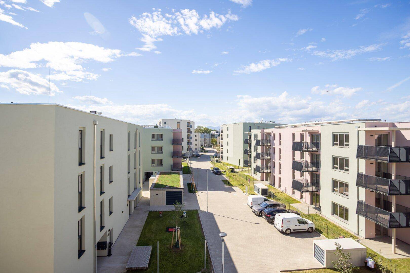 Überblick über eine moderne Wohnanlage mit farbigen Fassaden, Parkplätzen und gepflegten Grünflächen.