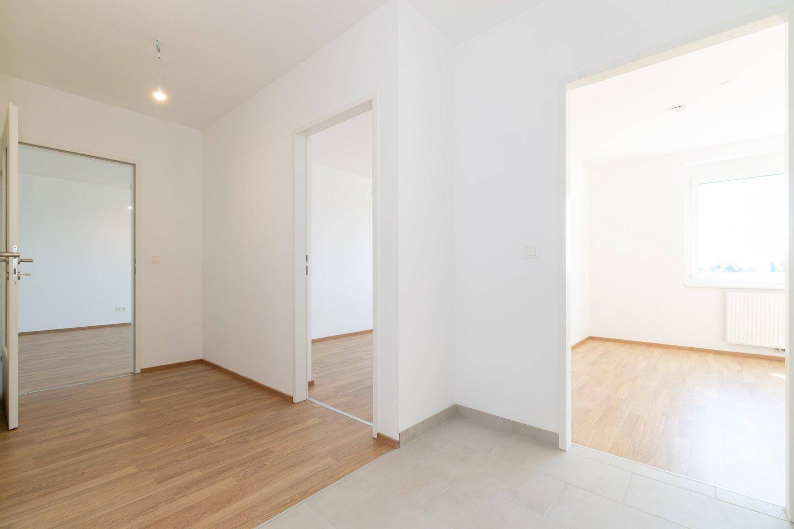 Geräumiger Flur mit unterschiedlichen Bodenbelägen und offenen Zugängen zu den Zimmern.