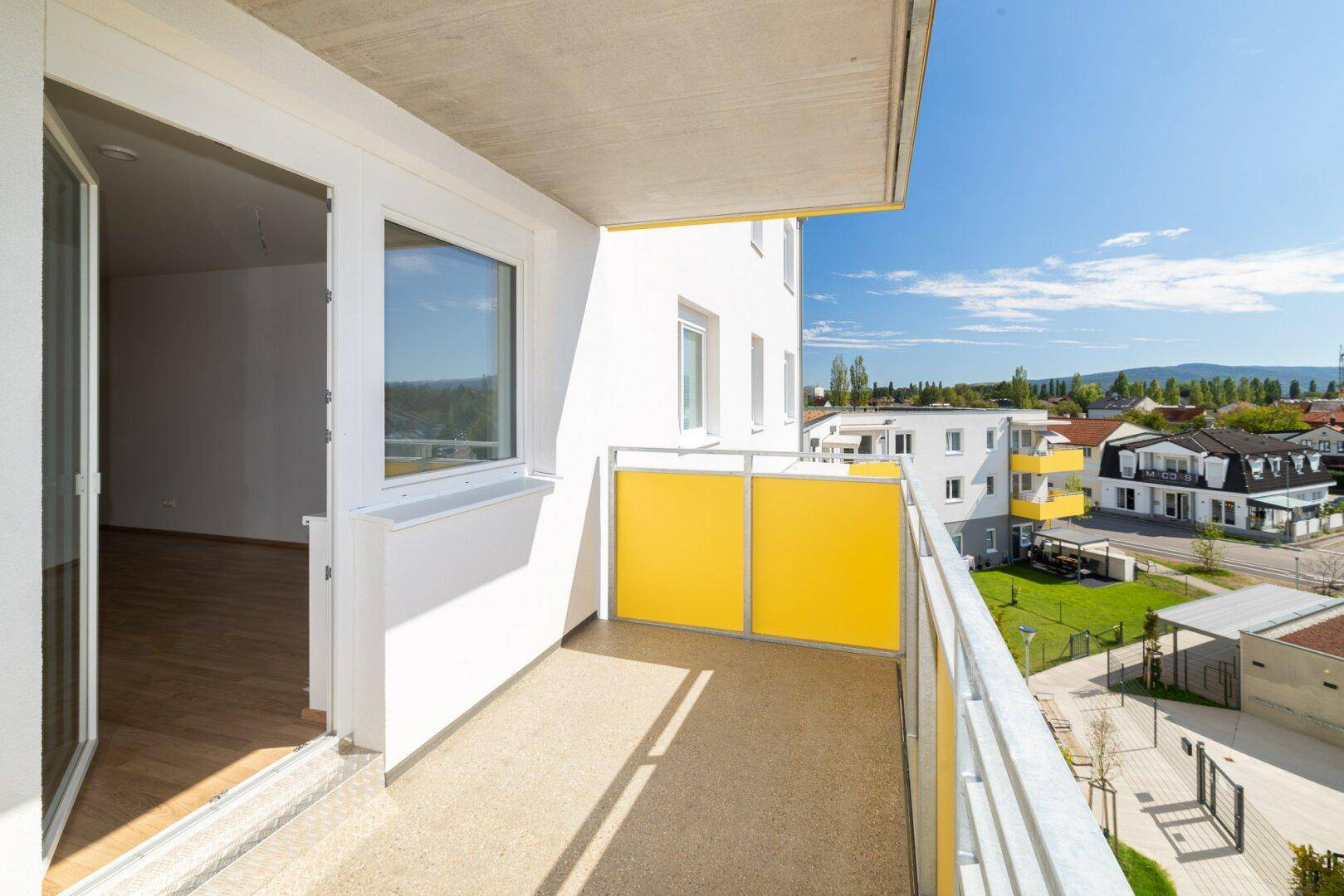 Heller Balkon mit Zugang zum Innenbereich und weitem Blick über die Umgebung.