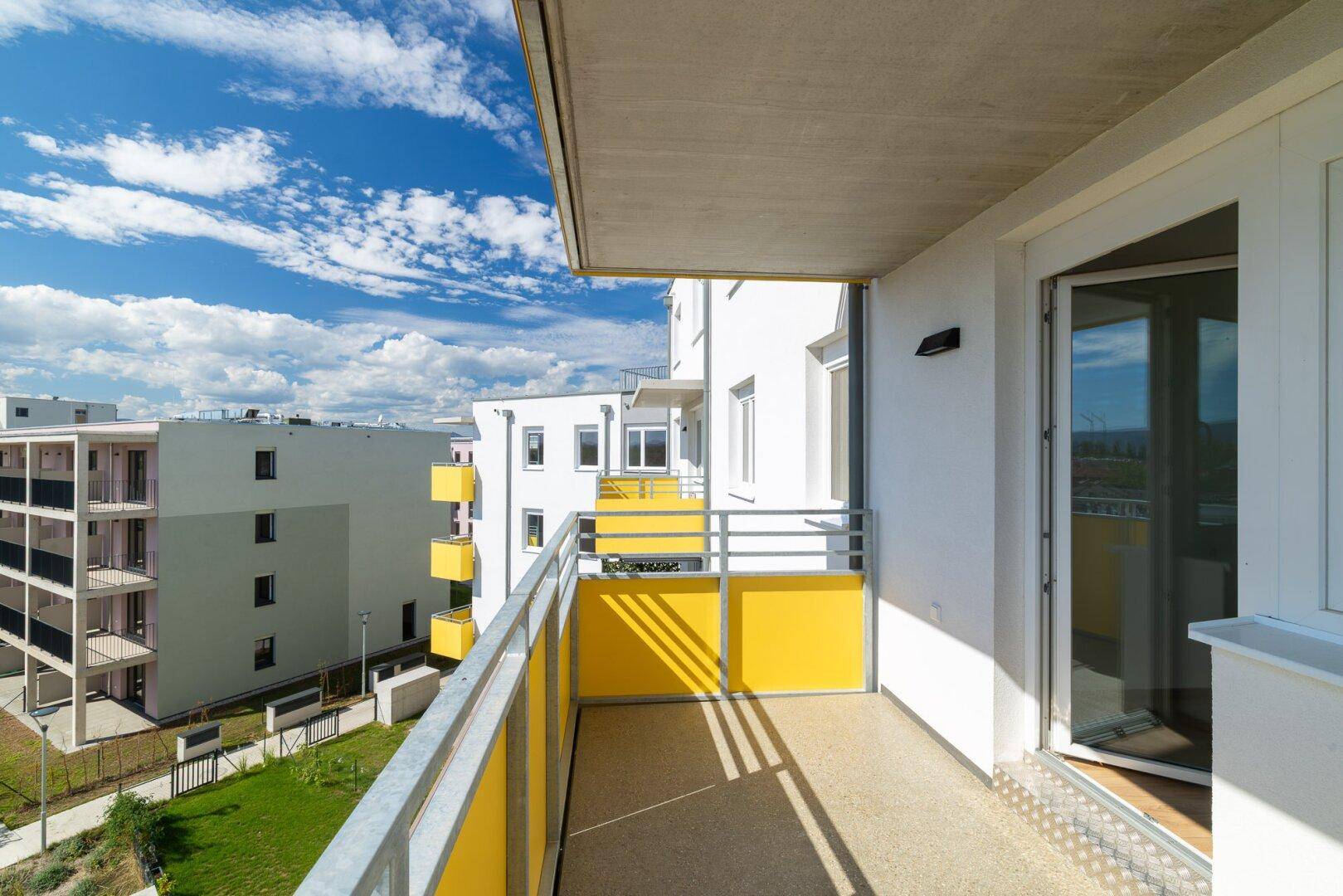 Heller Balkon mit Zugang zum Innenbereich und Blick auf die umliegenden Gebäude.