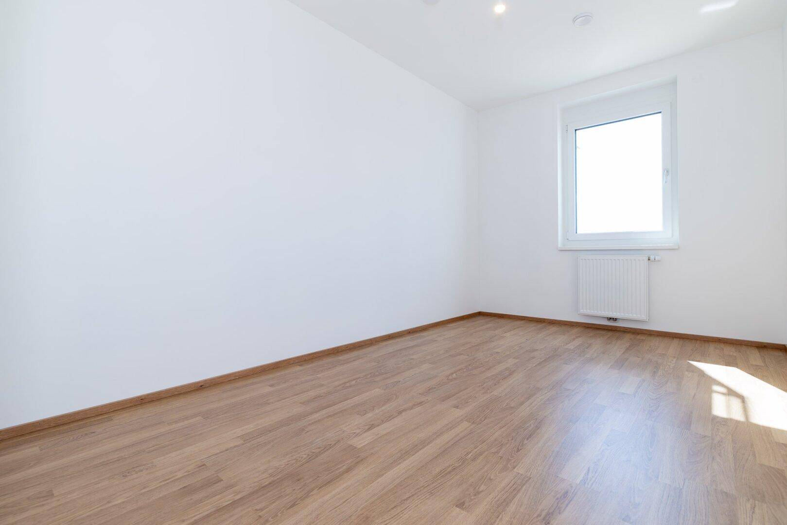 Geräumiges Schlafzimmer mit Laminatboden und einem Fenster, das viel Licht spendet.