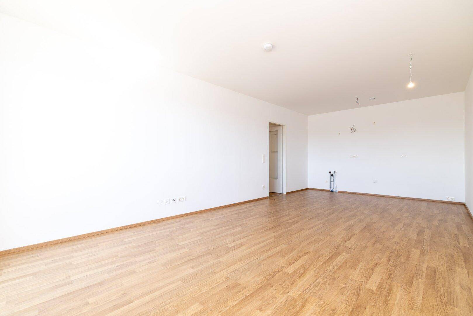 Leerer Raum mit Laminatboden, vorbereitet für die Installation einer Küche.