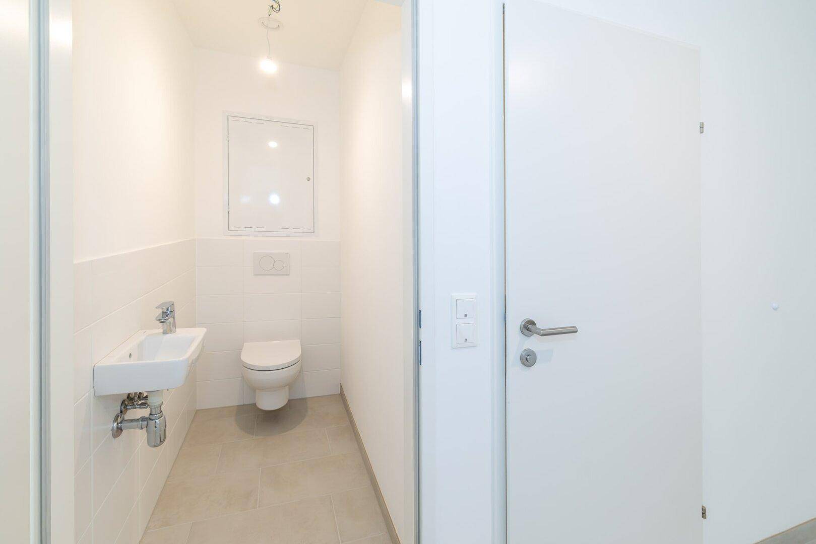 Funktionale Gästetoilette mit wandhängendem WC und kleinem Handwaschbecken.