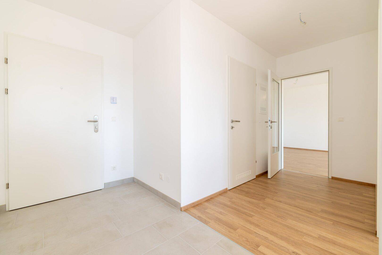 Geräumiger Flur mit Fliesen- und Laminatboden, der verschiedene Bereiche der Wohnung verbindet.
