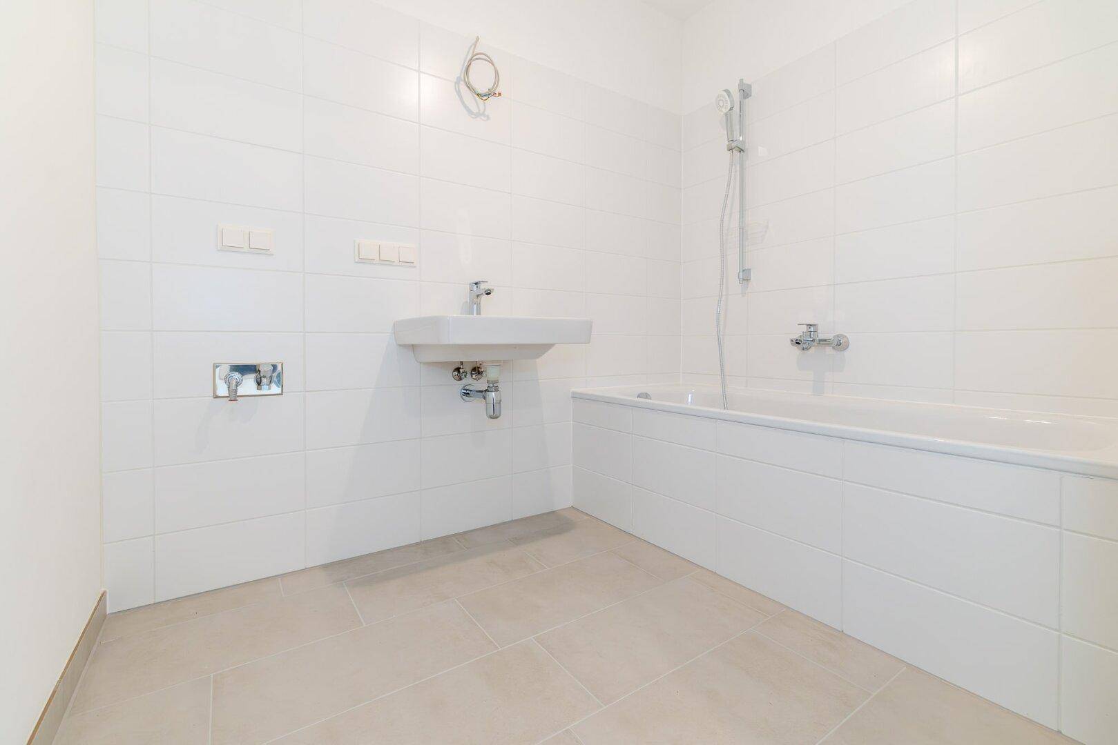 Modernes Badezimmer mit weißen Fliesen, Badewanne und einem Waschbecken.
