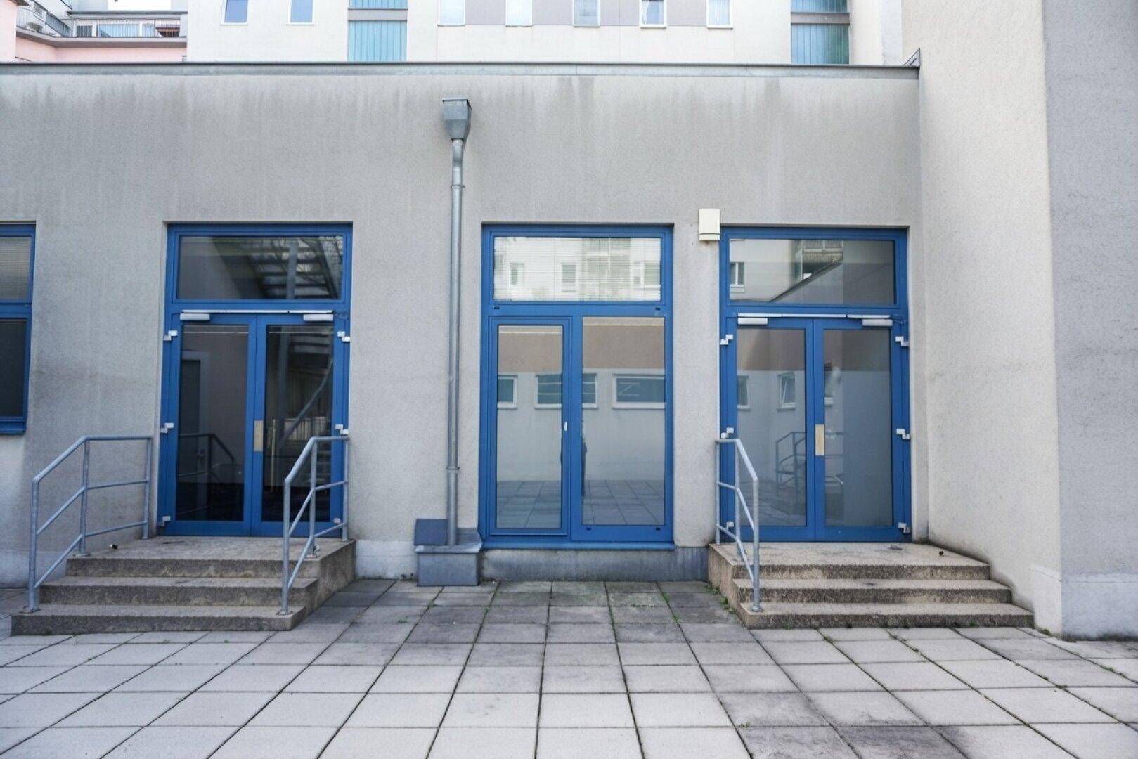 Gebäudefassade mit mehreren blauen Türen und Fenstern, die zu verschiedenen Einheiten führen.