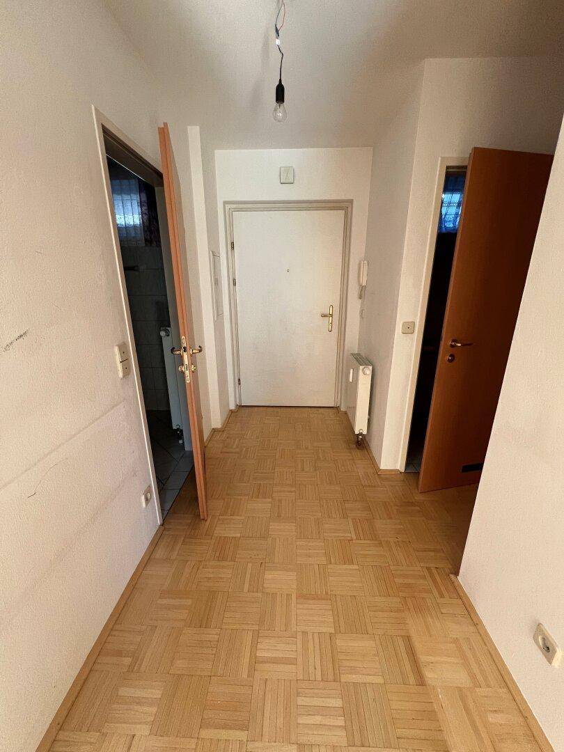 Heller Flur mit Parkettboden und mehreren Türen, der zu verschiedenen Räumen führt.