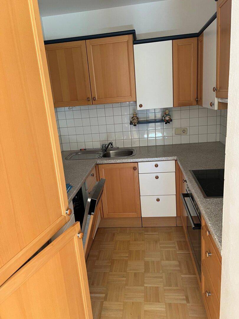 Funktionale Küche mit hellen Holzschränken, Fliesenrückwand und integrierten Geräten.