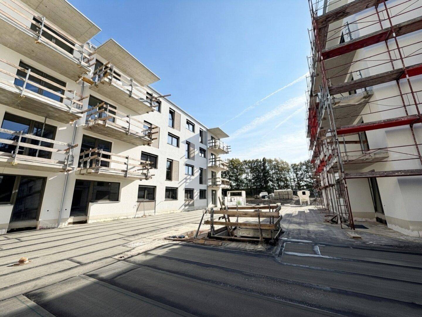 Neubauwohnungen im Bau mit moderner Architektur, großen Fenstern und Balkonen, umgeben von Gerüsten.