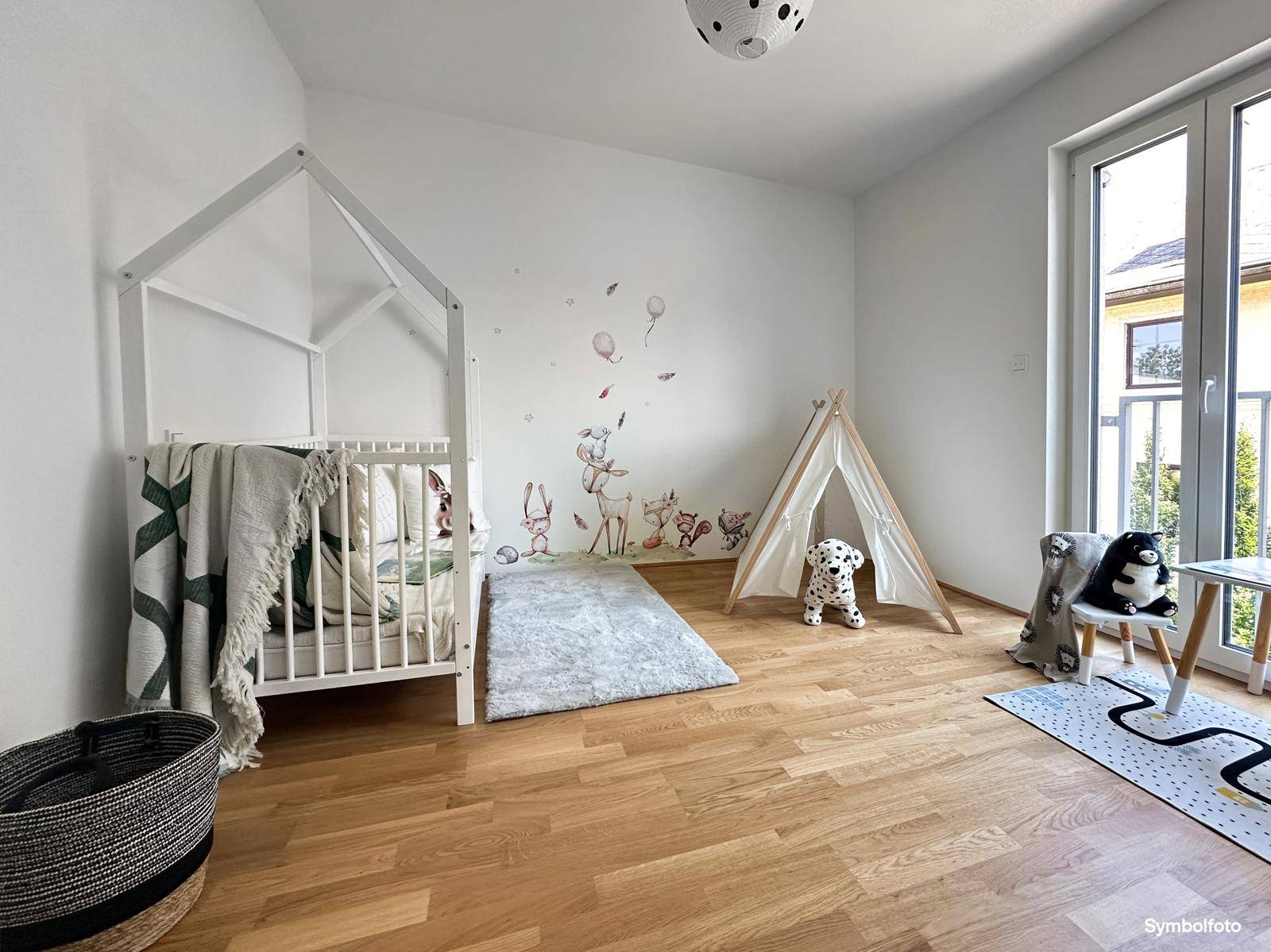 Helles Kinderzimmer mit Holzboden, Hausbett und Zugang zu einem kleinen Balkon oder französischen Balkon.