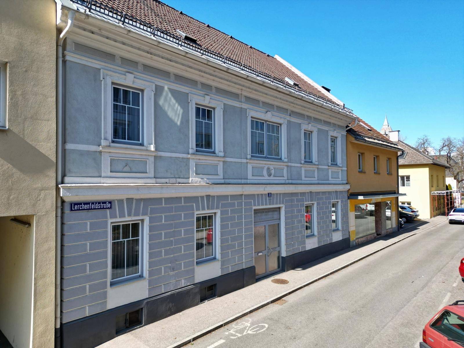 Historische Gebäudefassade mit einem Eingangsbereich und Blick auf die Straße an einem sonnigen Tag.