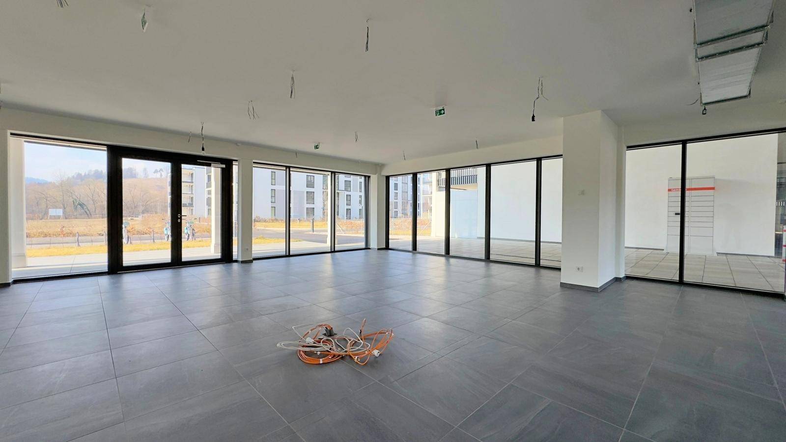 Weitläufiger Gewerberaum mit Blick auf die Umgebung durch die großen Fenster.