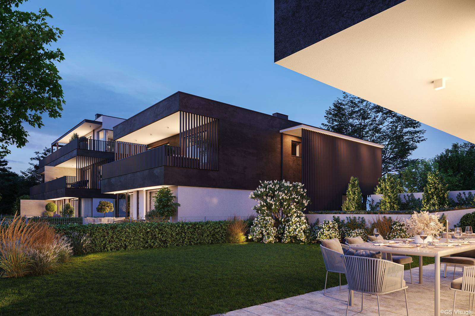 Abendliche Ansicht einer modernen Wohnanlage mit beleuchtetem Garten und Terrasse.
