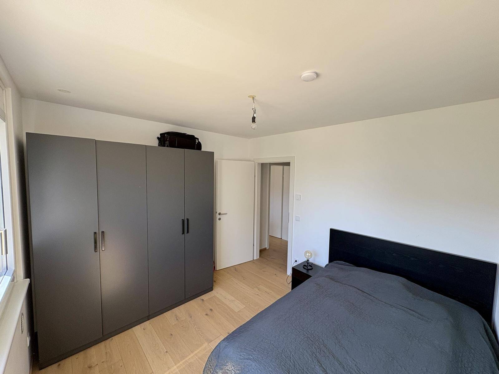 Schlafzimmer mit Holzboden, großem Kleiderschrank und Doppelbett.