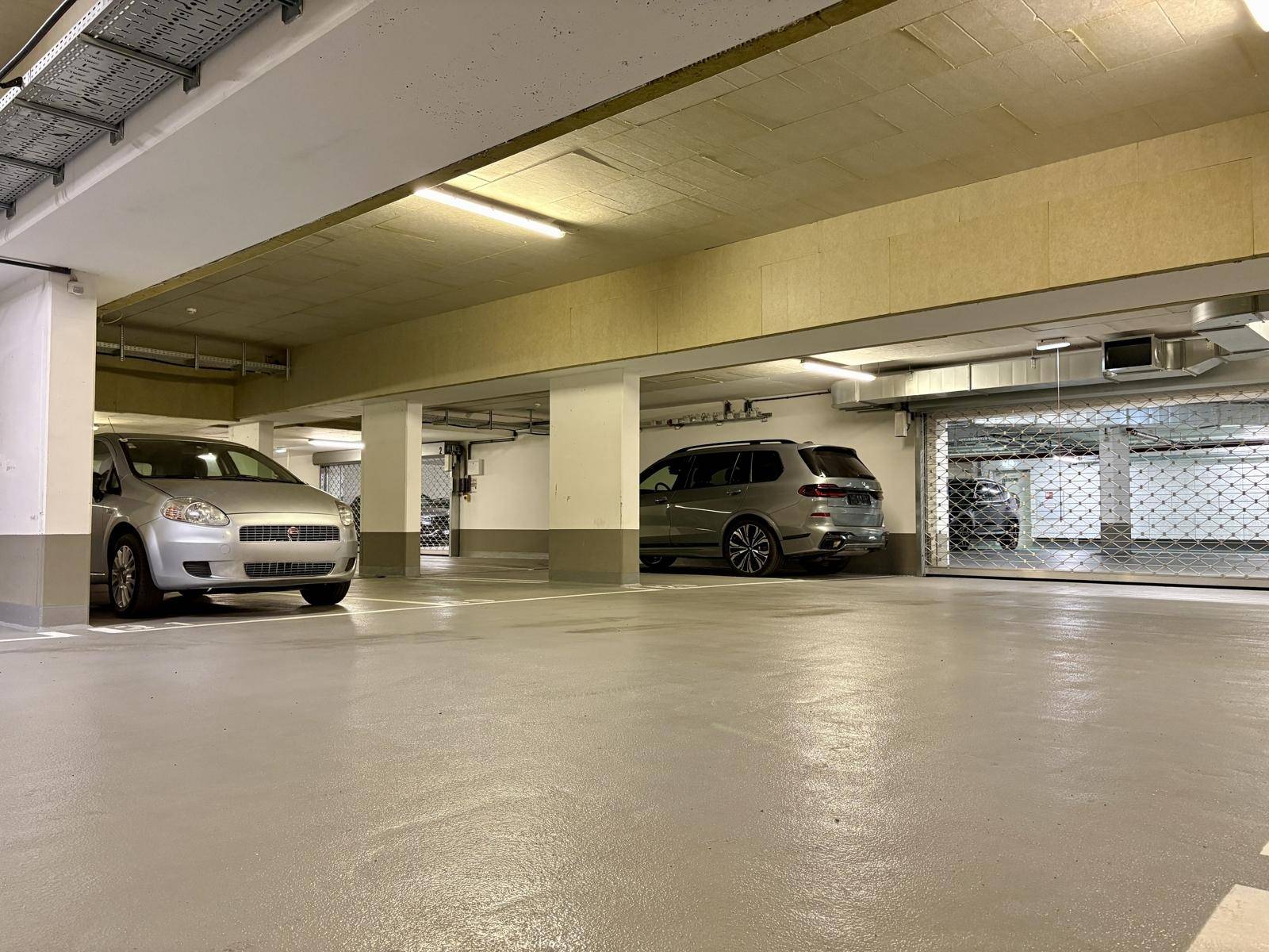 Tiefgarage mit mehreren Stellplätzen und geparkten Fahrzeugen.