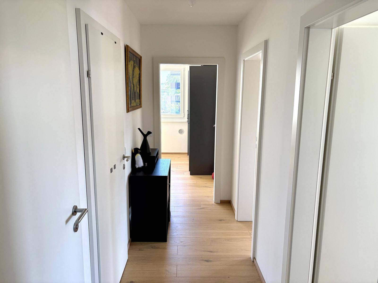 Heller Flur einer Wohnung mit Holzboden und mehreren Türen zu den Zimmern.