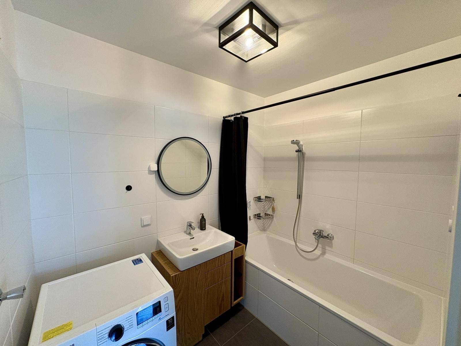 Modernes Badezimmer mit Badewanne, Waschbecken und Waschmaschine.