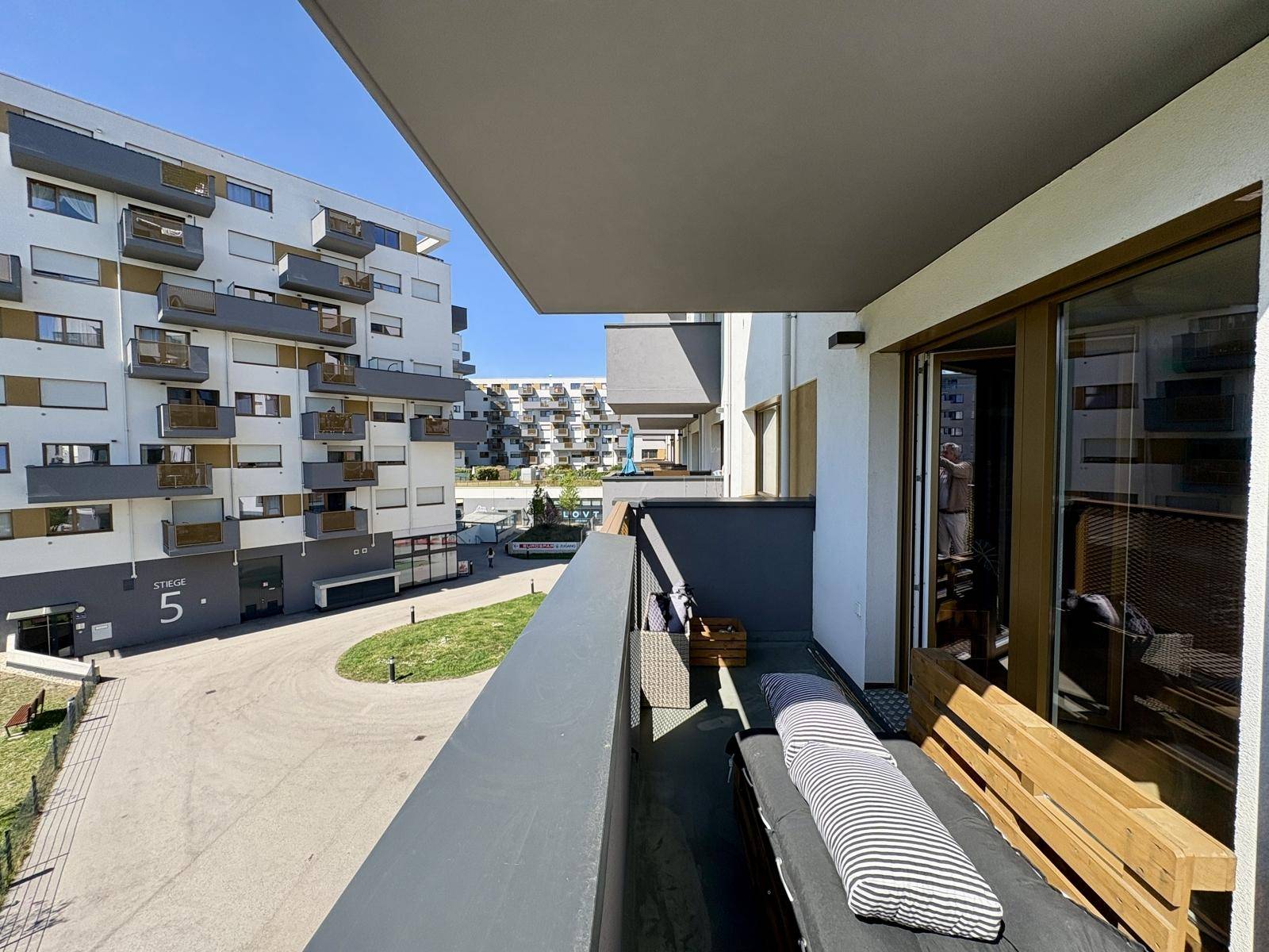 Geräumiger Balkon mit Liege und Blick auf die moderne Wohnanlage.