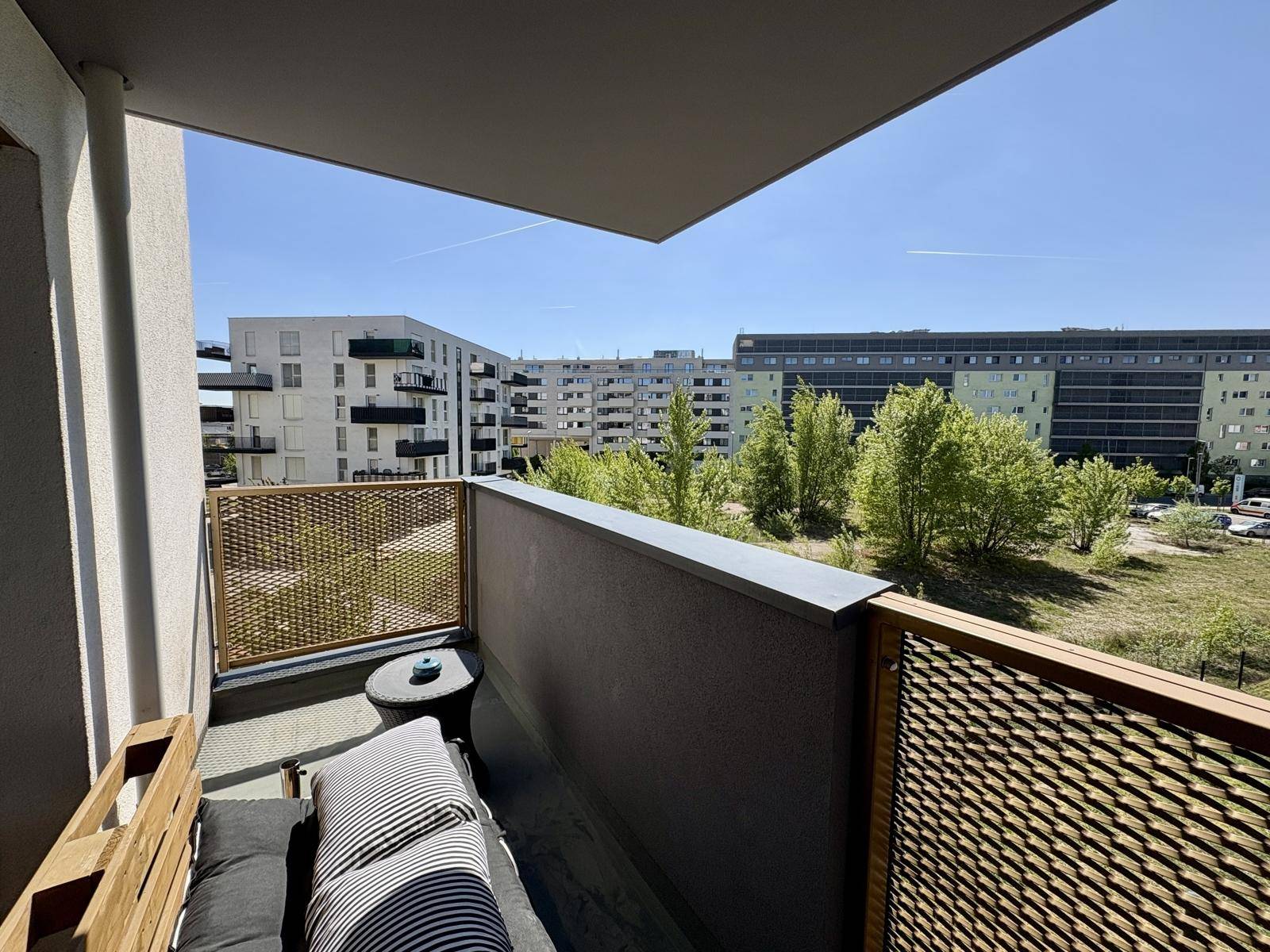Möblierter Balkon mit Blick auf die umliegenden Wohngebäude und Grünflächen.