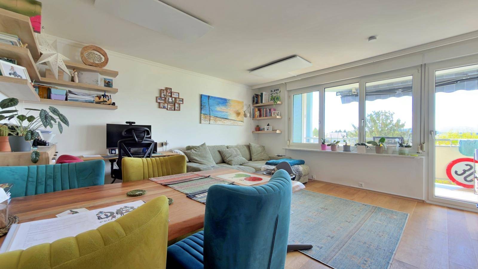 Heller Wohn- und Essbereich mit großem Sofa, Esstisch und Zugang zum Balkon.