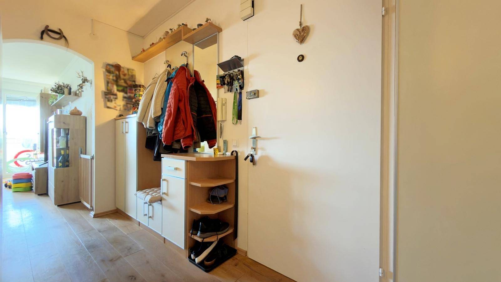 Heller Eingangsbereich mit Garderobe, Schuhablage und Holzboden.