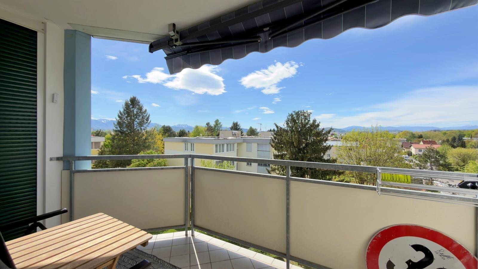 Gemütlicher Balkon mit Holztisch und Markise, bietet einen weiten Blick über die Umgebung.