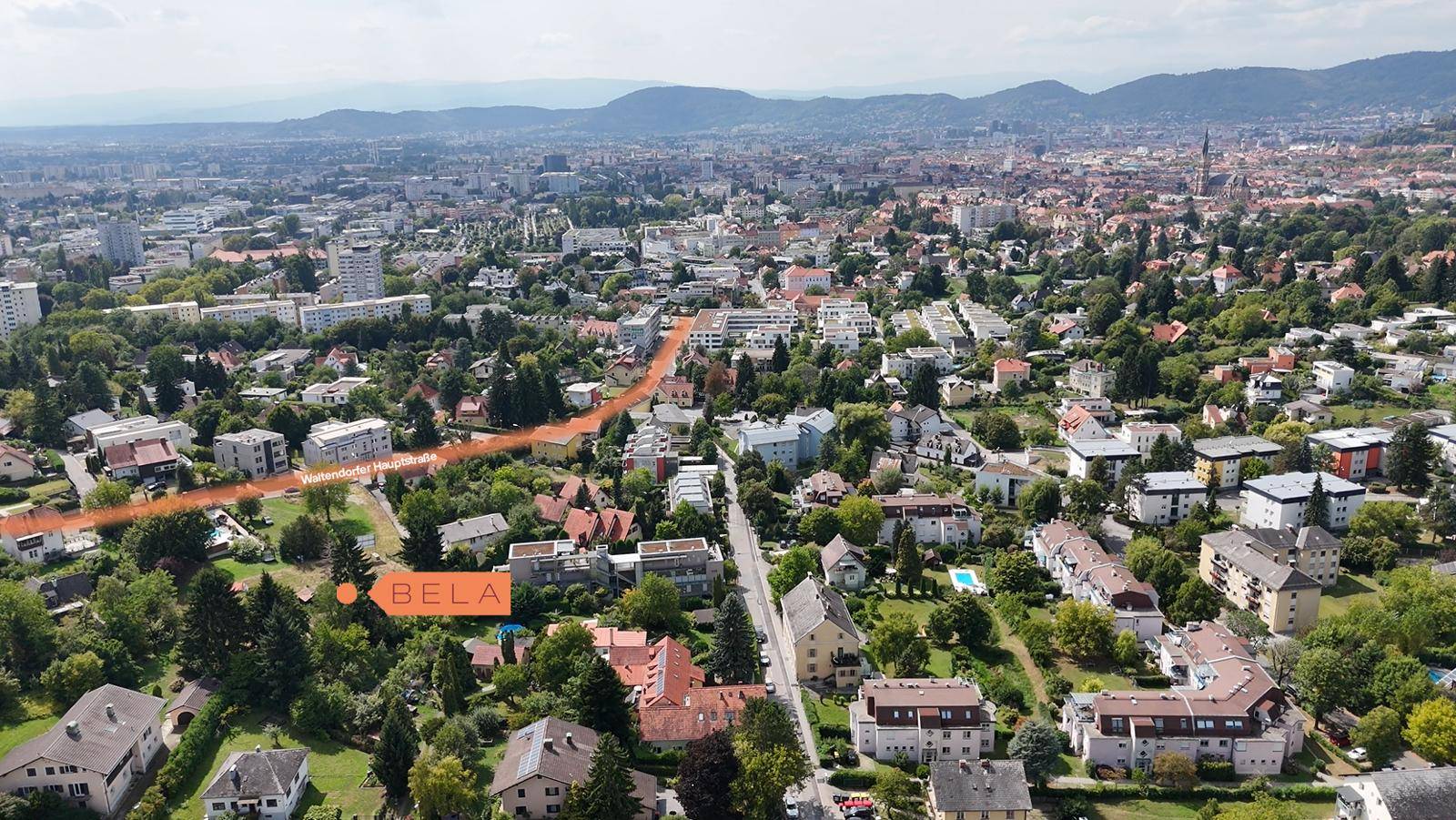 Luftaufnahme einer Stadt mit Wohngebieten, grünen Flächen und einer markierten Straße.