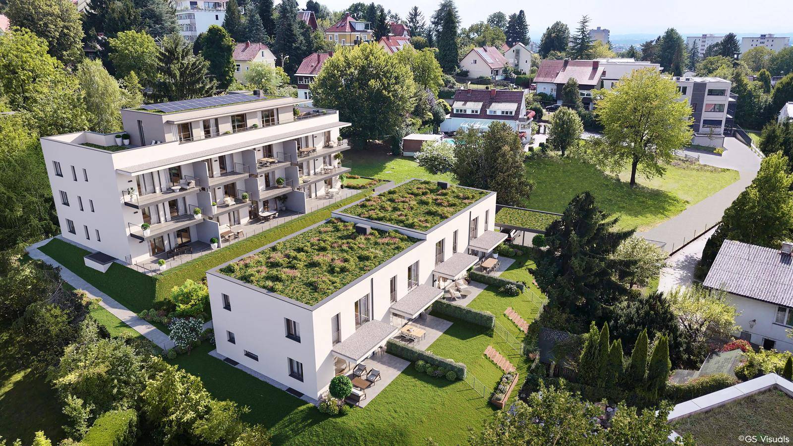 Moderne Wohnanlage mit begrünten Dächern, umgeben von viel Grün und Einfamilienhäusern.