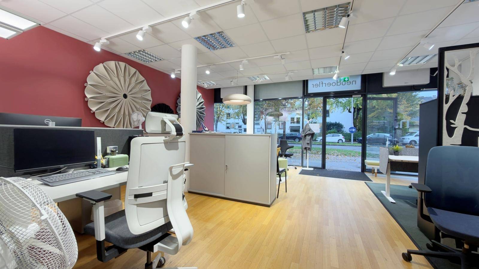 Moderner Bürobereich mit Arbeitsplatz, ergonomischem Stuhl und großen Fenstern mit Blick auf die Umgebung.