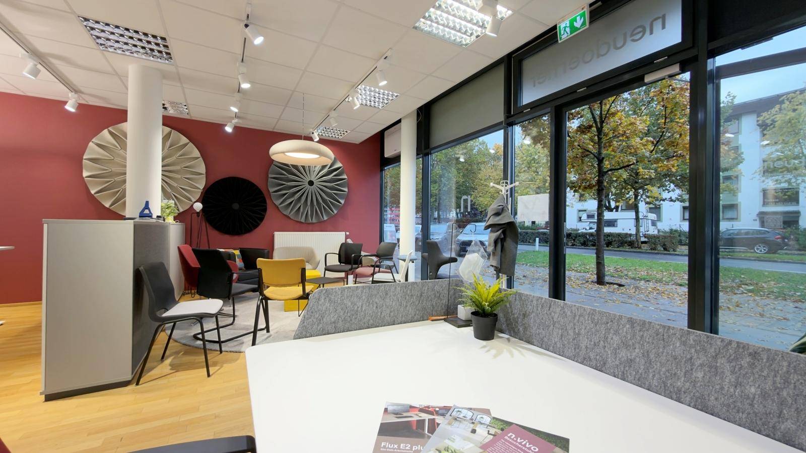 Moderner Bürobereich mit Schreibtisch im Vordergrund und einem stilvollen Loungebereich mit dekorativen Wandpaneelen.