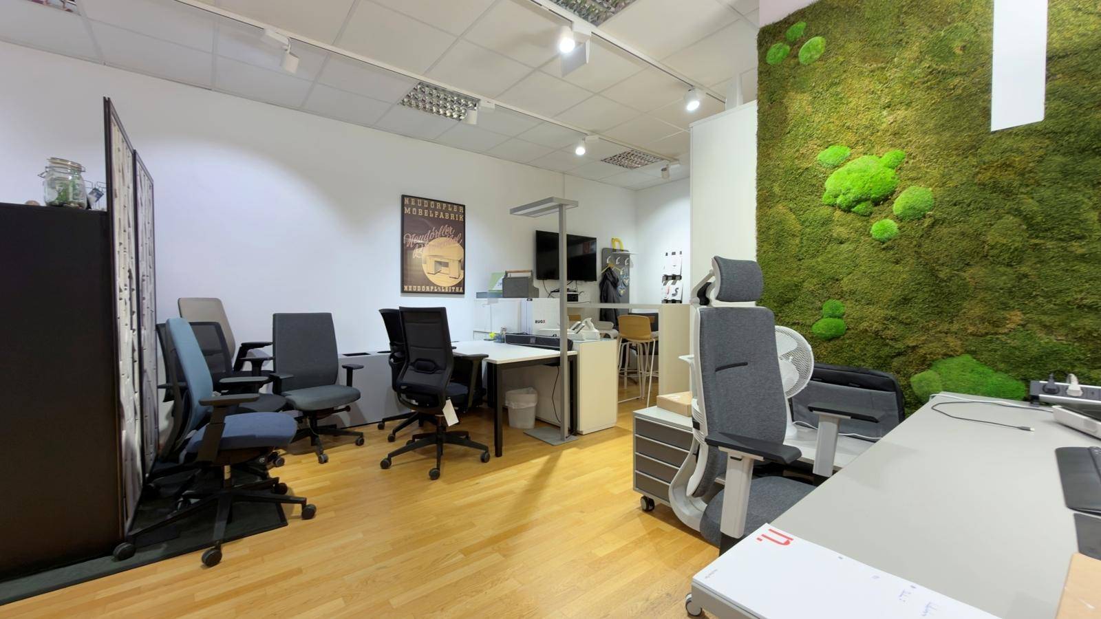 Geräumiger Bürobereich mit mehreren Arbeitsplätzen, ergonomischen Bürostühlen und einer auffälligen Mooswand.