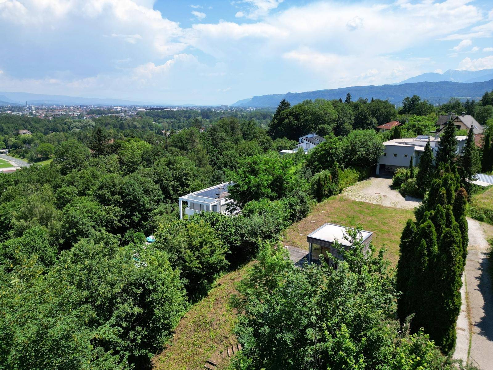 Weitläufige Luftaufnahme des Grundstücks mit Blick auf moderne Architektur, Stadt und Berge.