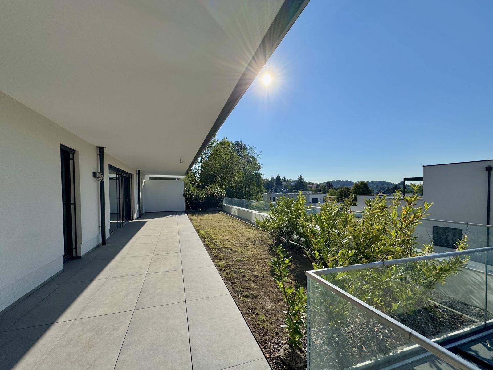 Große, sonnige Terrasse mit Fliesenboden und Blick ins Grüne, ideal für Entspannung.